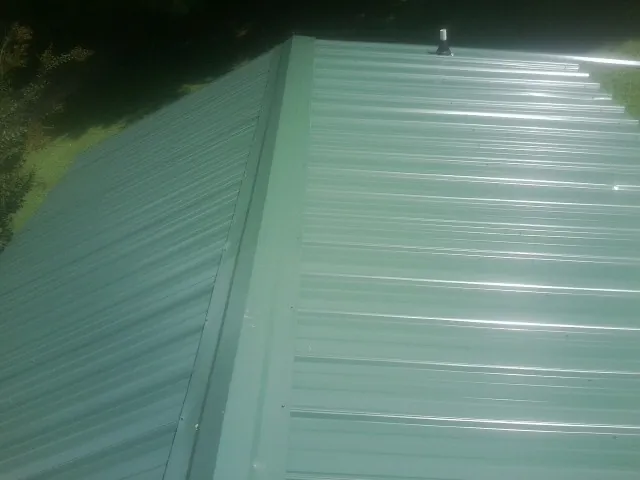 New green metal panels meeting at the ridge of a roof — Flat Roof Repair work by our crew in Flemington
