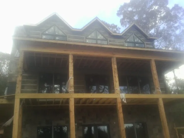 Dormers and porch framing on a large log home under construction — Roof Coating work by our crew in Flemington