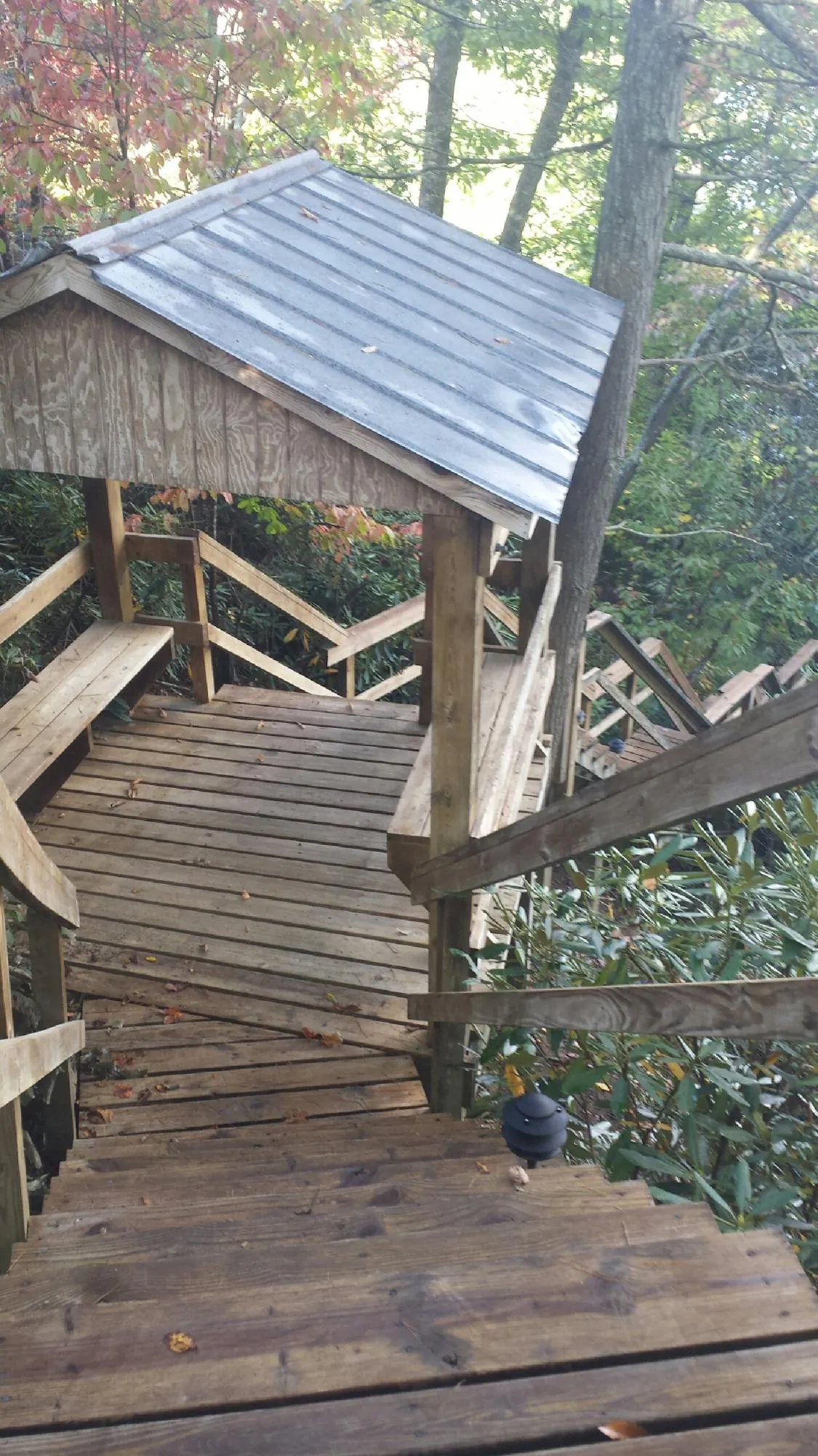 Metal roofed shelter over wooden steps on a wooded walkway — Skylight Repair & Installation work by our crew in Flemington